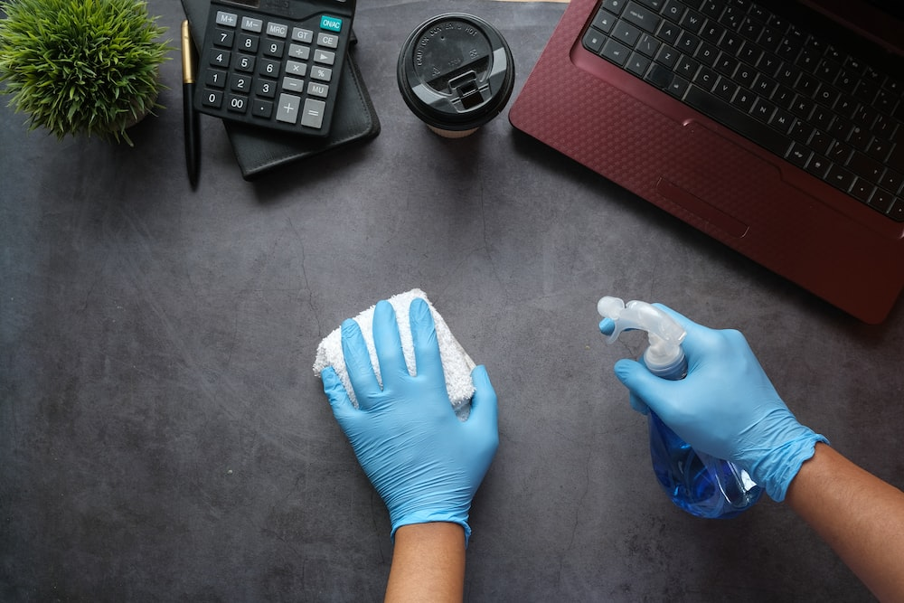 professional cleaner sanitizing a work desk
